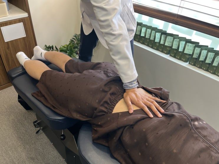 엎드린 환자의 허리를 손으로 누르는 모습