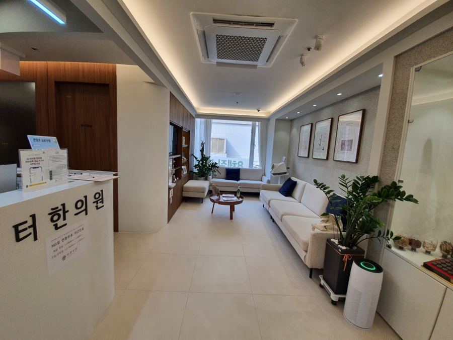 접수대와 소파, 화분이 있는 병원 대기실 사진