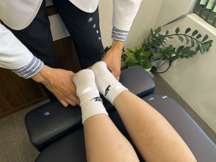 의료진이 누운 환자의 양쪽 발목을 잡아 검사하는 사진