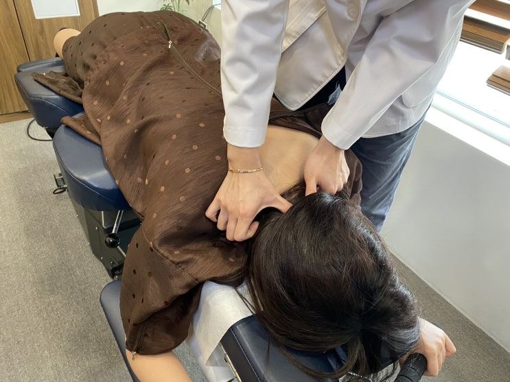 엎드린 환자의 목과 어깨를 손으로 치료하는 장면