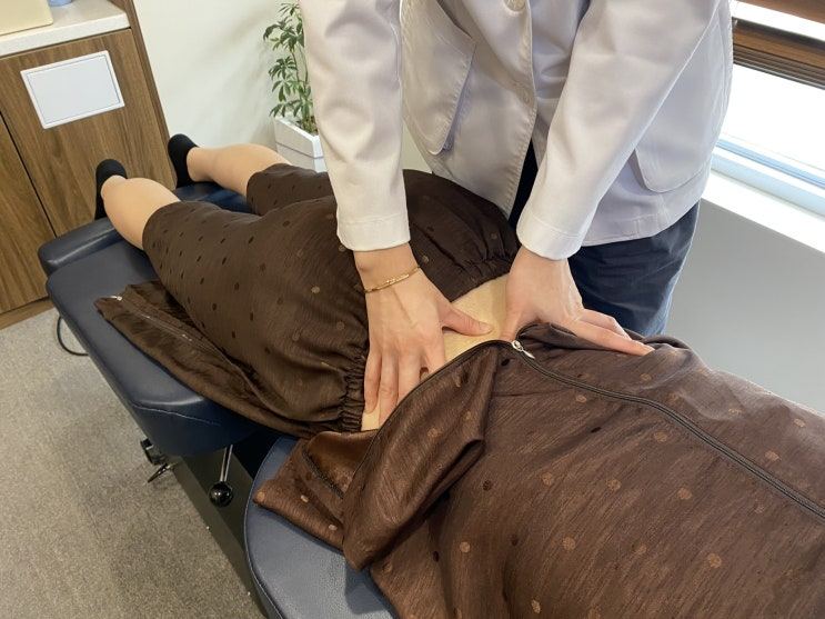 엎드린 환자의 허리 부위를 양손으로 누르는 치료 장면